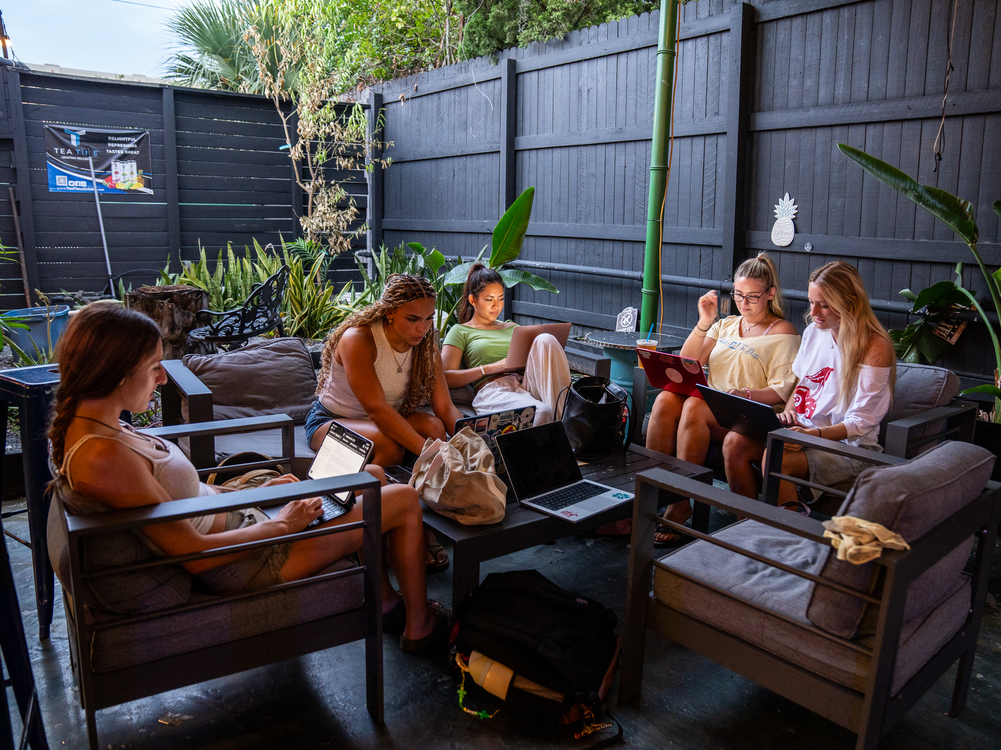 Friends hanging out and working on laptops in the Kava & Company backyard patio
