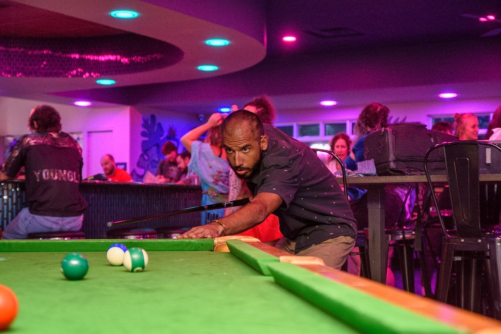 Friends playing pool during an event night at Kava & Company