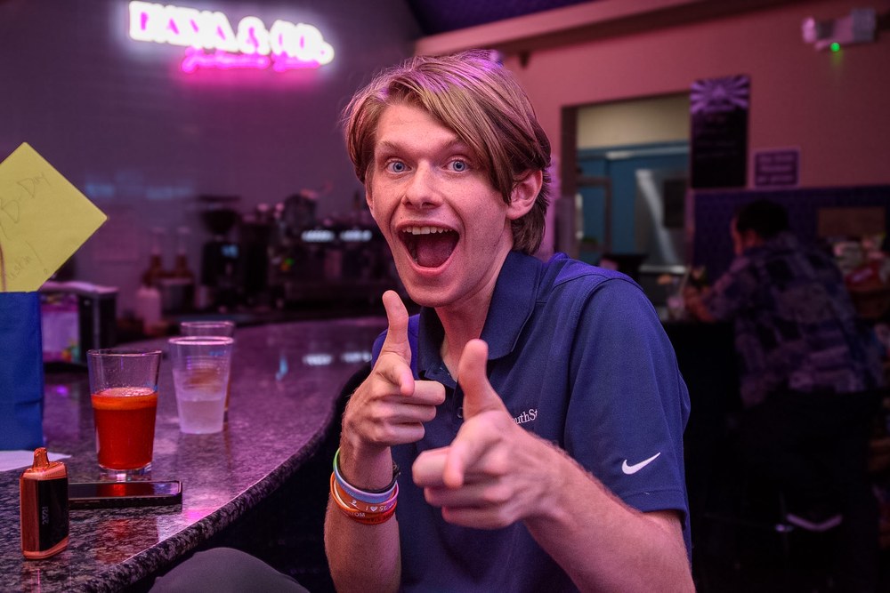 Guest having fun under the neon KAVA & CO sign
